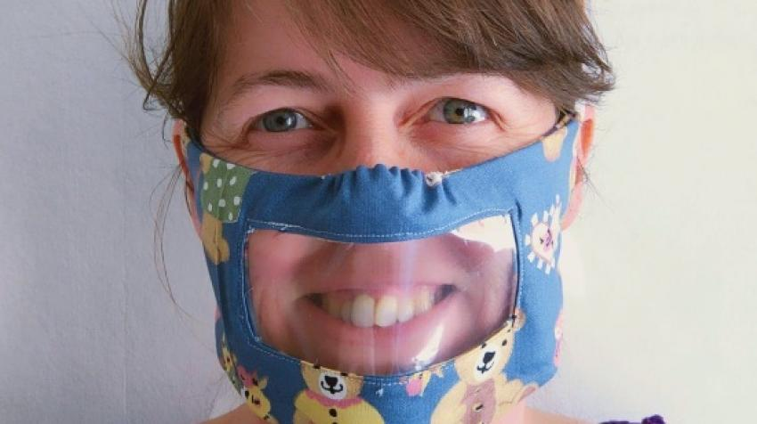 Une jeune femme essaie un masque transparent conçu pour aider les sourds et malentendants.