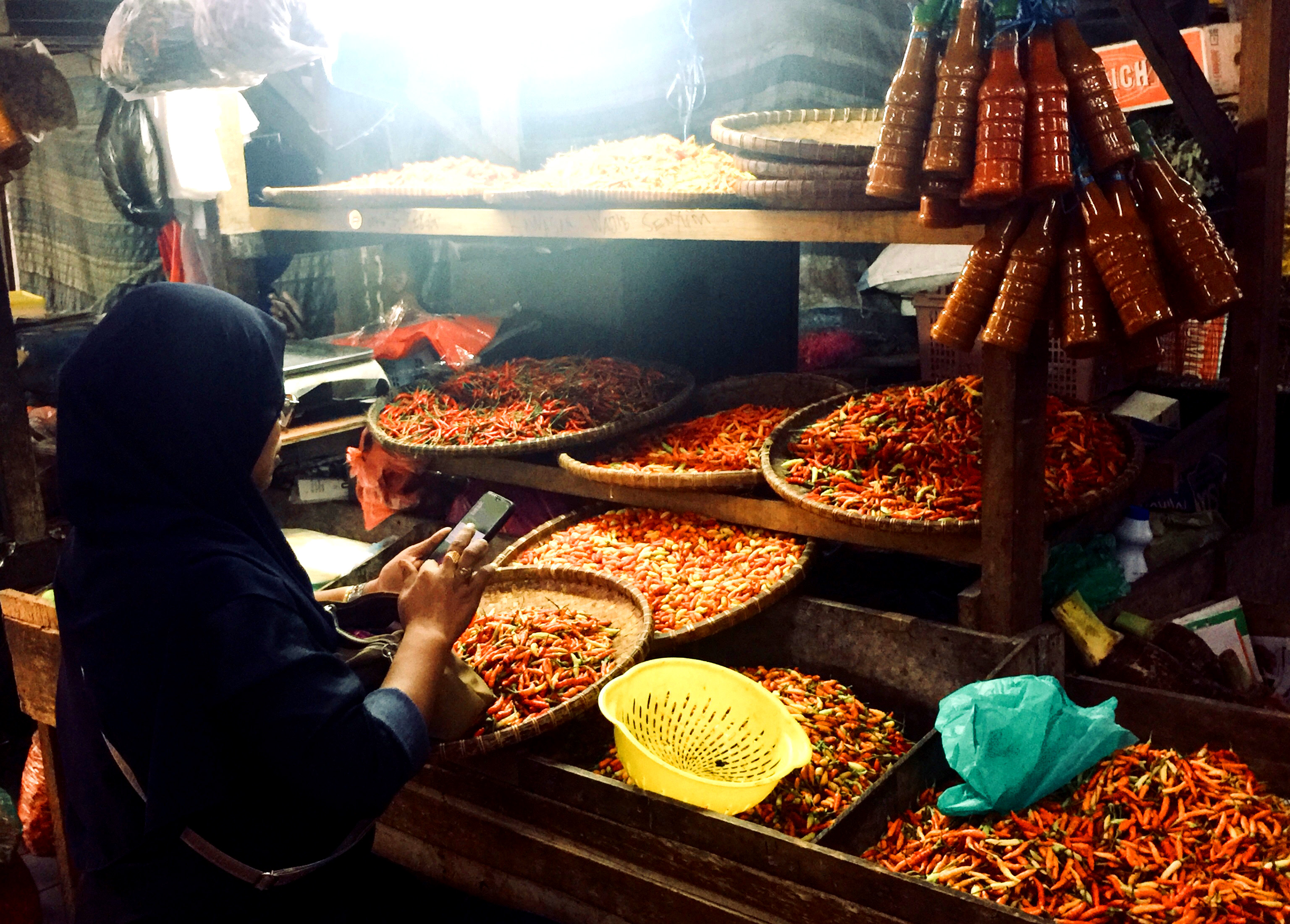 A woman works on her phone while shopping in a market.