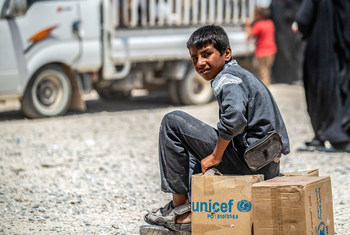 A boy sits on top of a box that reads UNICEF.