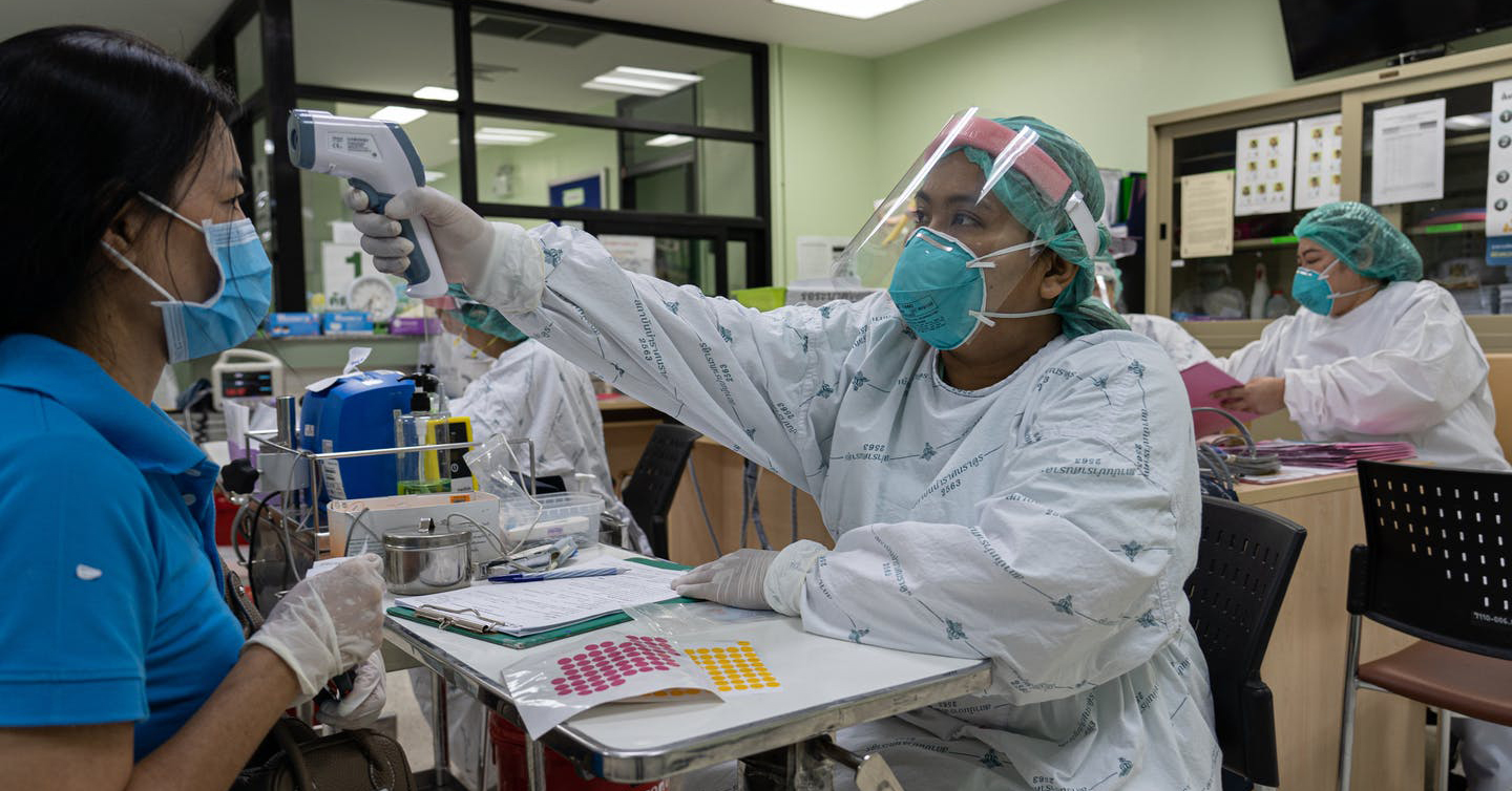 A healthcare worker checks the temperature of a patient at a hospital in Nonthaburi Province, Thailand.