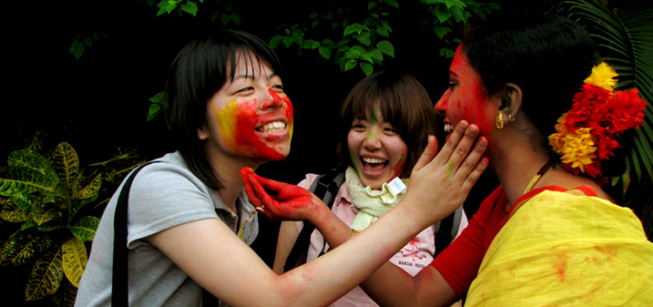 Turistas coreanas y una local en India pintándose la cara en una celebración tradicional