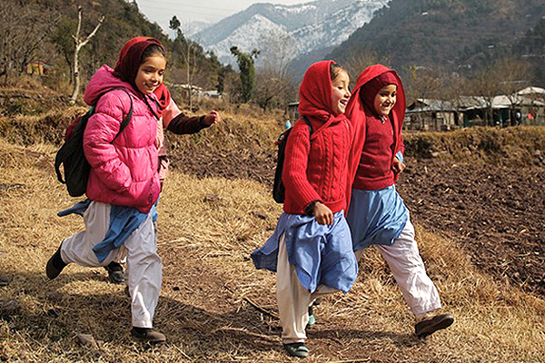 Three girls walking side-by-side on a mountain path. 