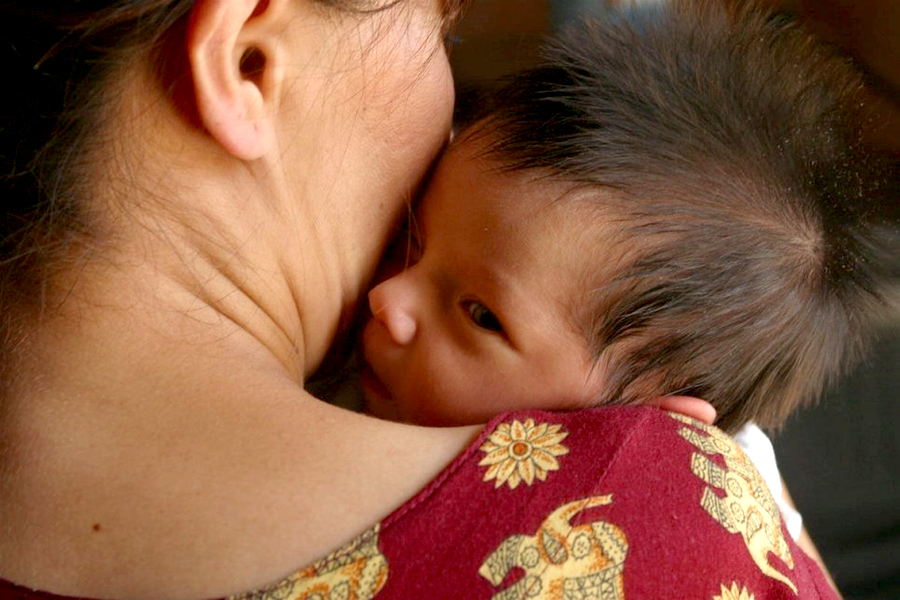 A baby rests his/her head on a woman’s shoulder.
