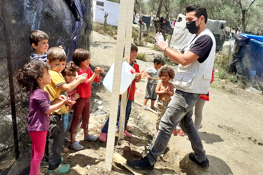 A man teaches children how to wash their hands.