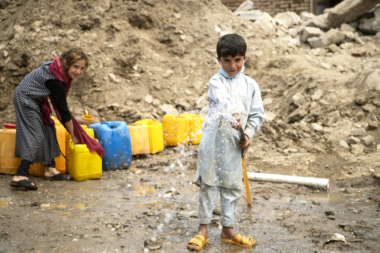 Children collect water in a neighborhood devastated by the floods.