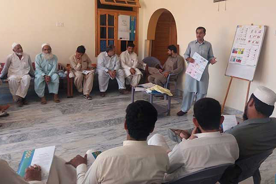 A man stands in front of a group with charts and graphs. 