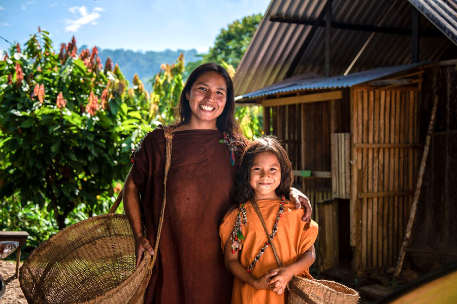 An indigenous woman and her daughter smile.