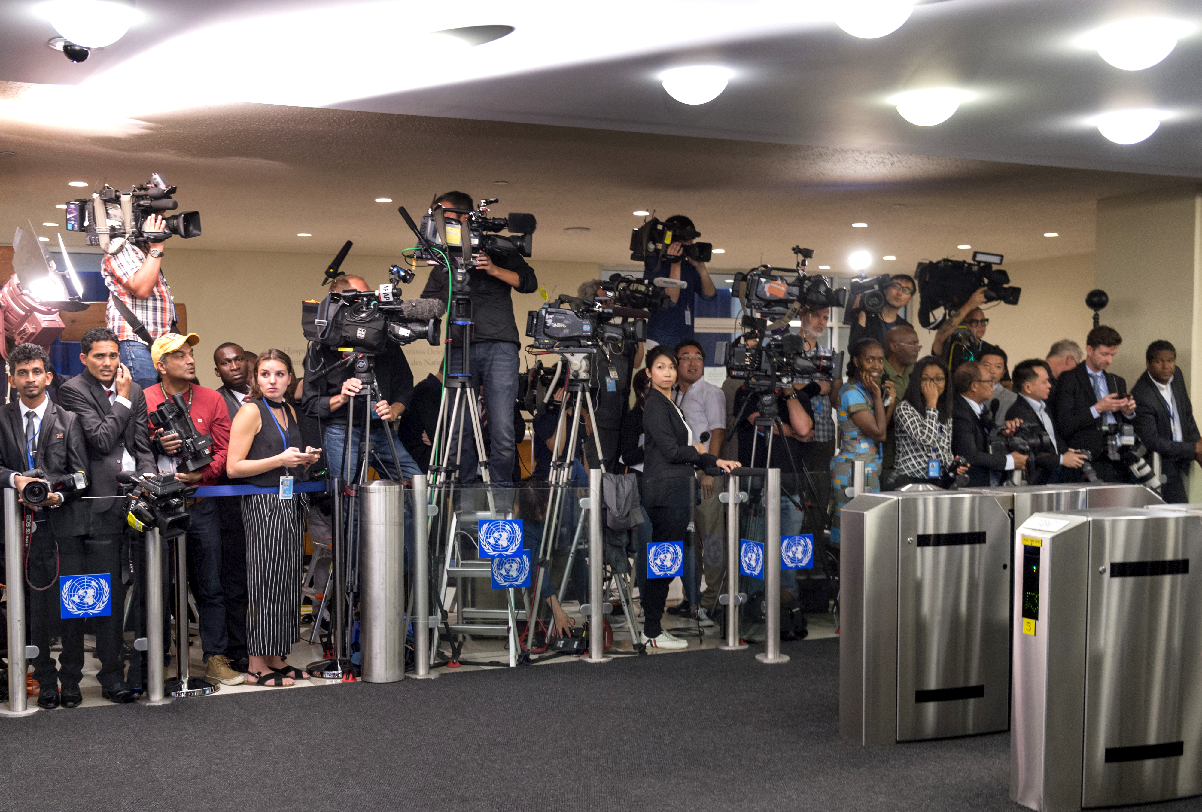 Journalists congregate and wait behind an entrance.