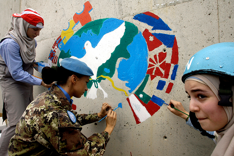 women painting mural on peace