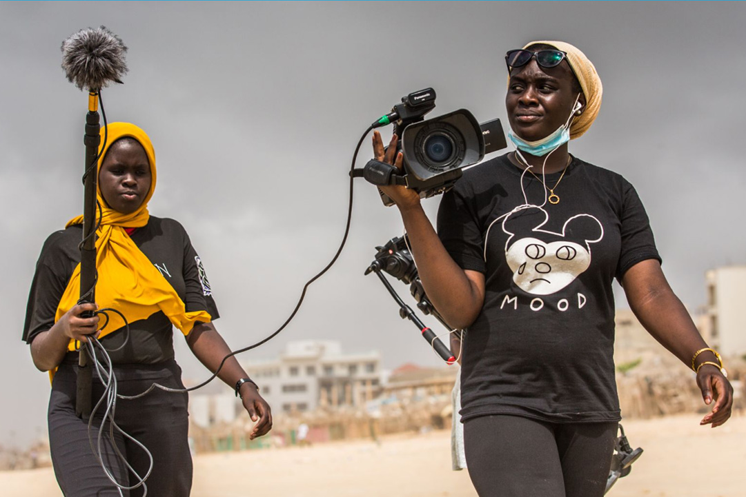 Oumou Kalsoum Diop with her camera followed by young woman with microphone
