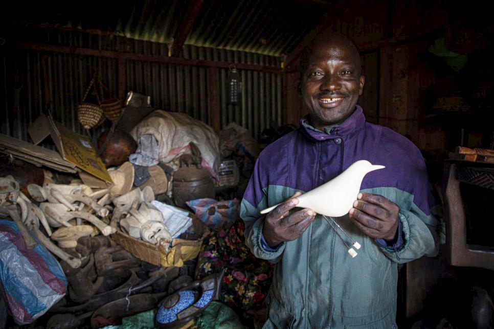 Artisan Kapya Kitungwa holds a wooden dove