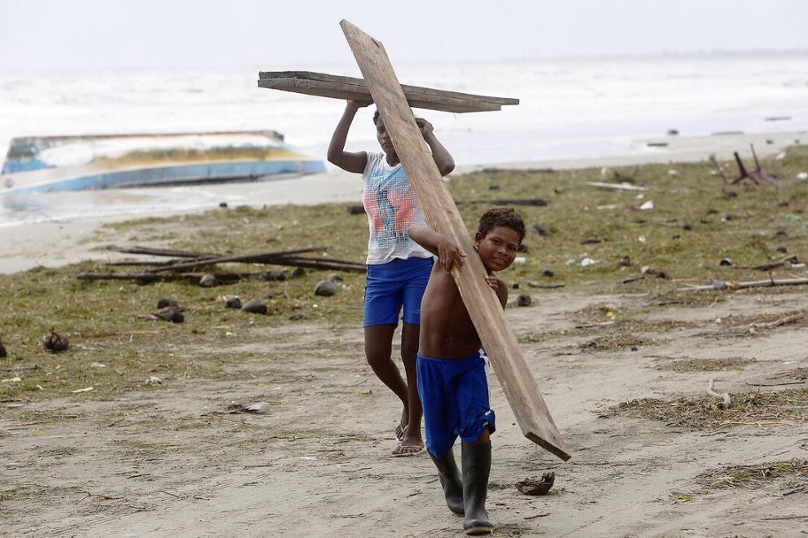 People salvage wooden beams to rebuild destroyed structures.