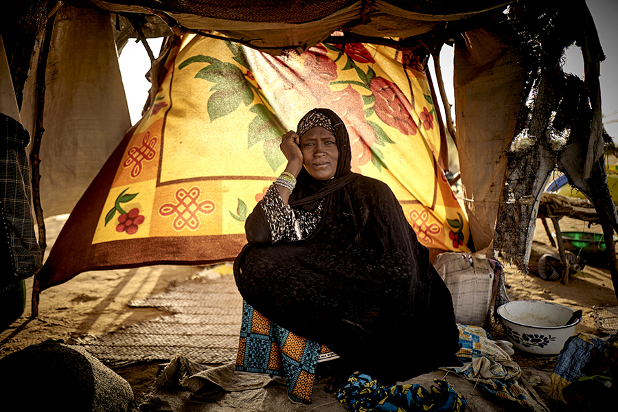 A woman sits inside a makeshift shelter. 