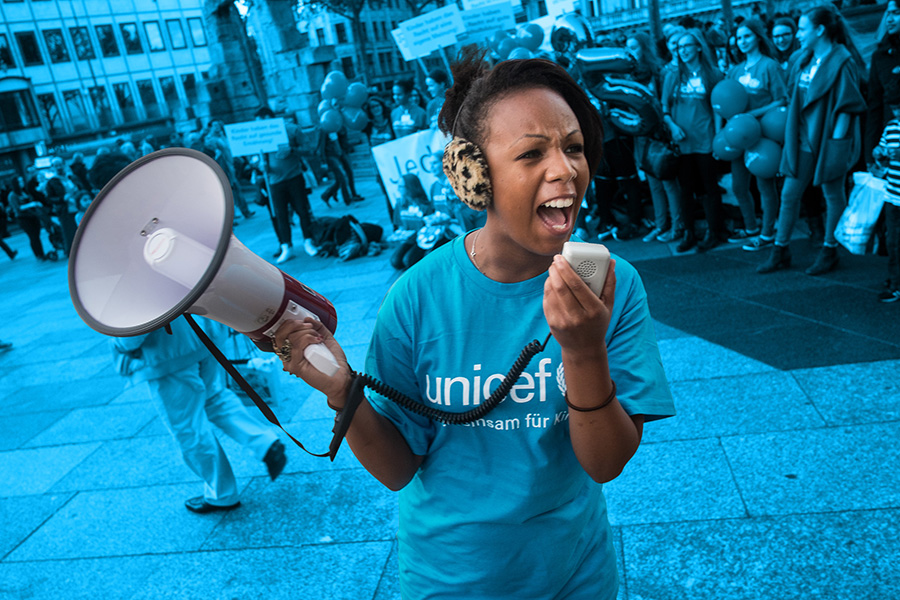 Girl wearing a UNICEF t-shirt speaks into a bullhorn. 