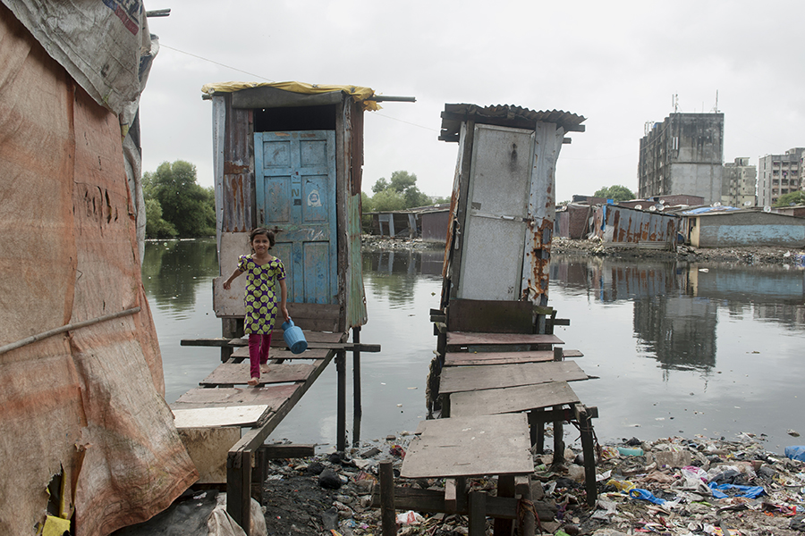 Girl walks out of a small shack on stilts into a path on stilts. 