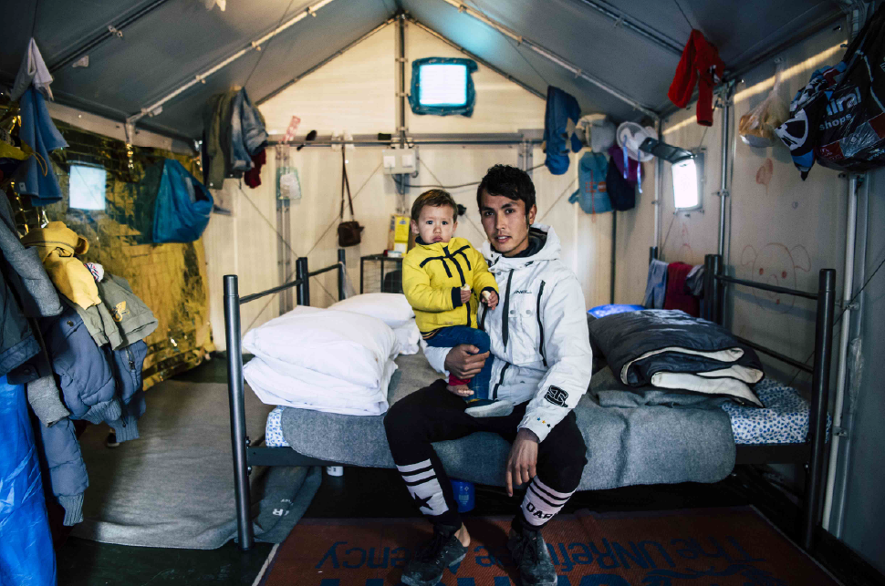 A father sits with his son in a winterized tent on the Greek island of Lesvos.