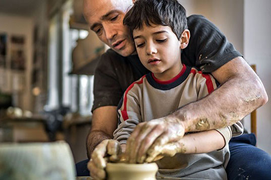 father teaching son pottery making