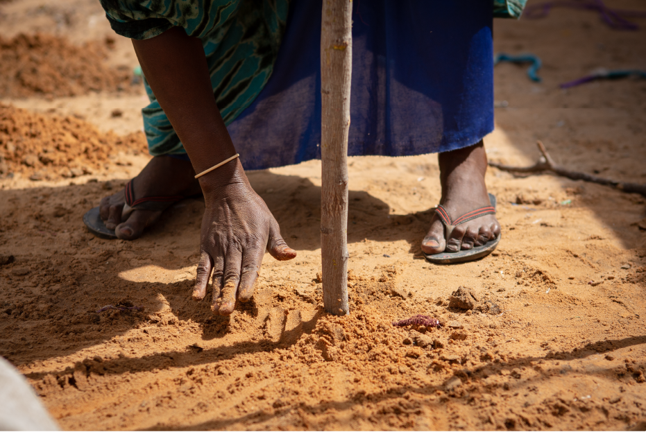 Khadija Ibrahim fixes the sand on the ground where the sticks used for constructing makeshift homes are inserted on the ground.