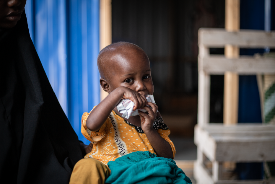 Portrait of Ruweydha Abdi enjoying her Ready To Use Therapeutic Food (RUTF) at a health center in Kahda IDP camp in Mogadishu, Somalia.