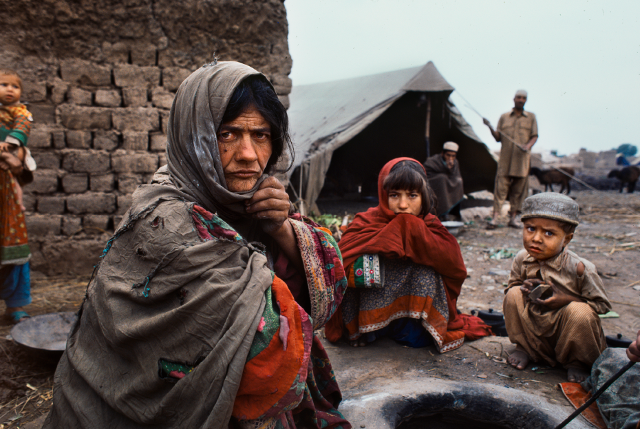 Woman and her children sitting around a pit at a refugee camp.