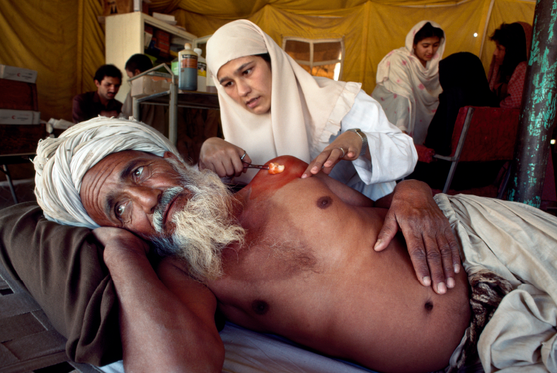 An Afghan nurse tends an old man in a Red Crescent clinic at the Kachaghari refugee camp.