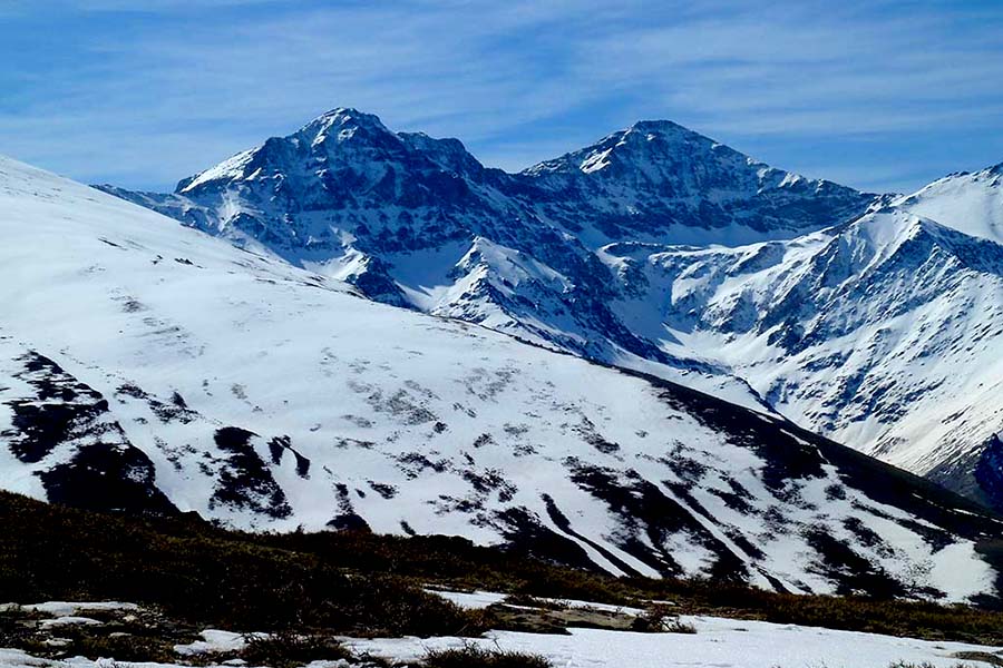Two snowed mountain peaks with rugged and vertical north faces. 