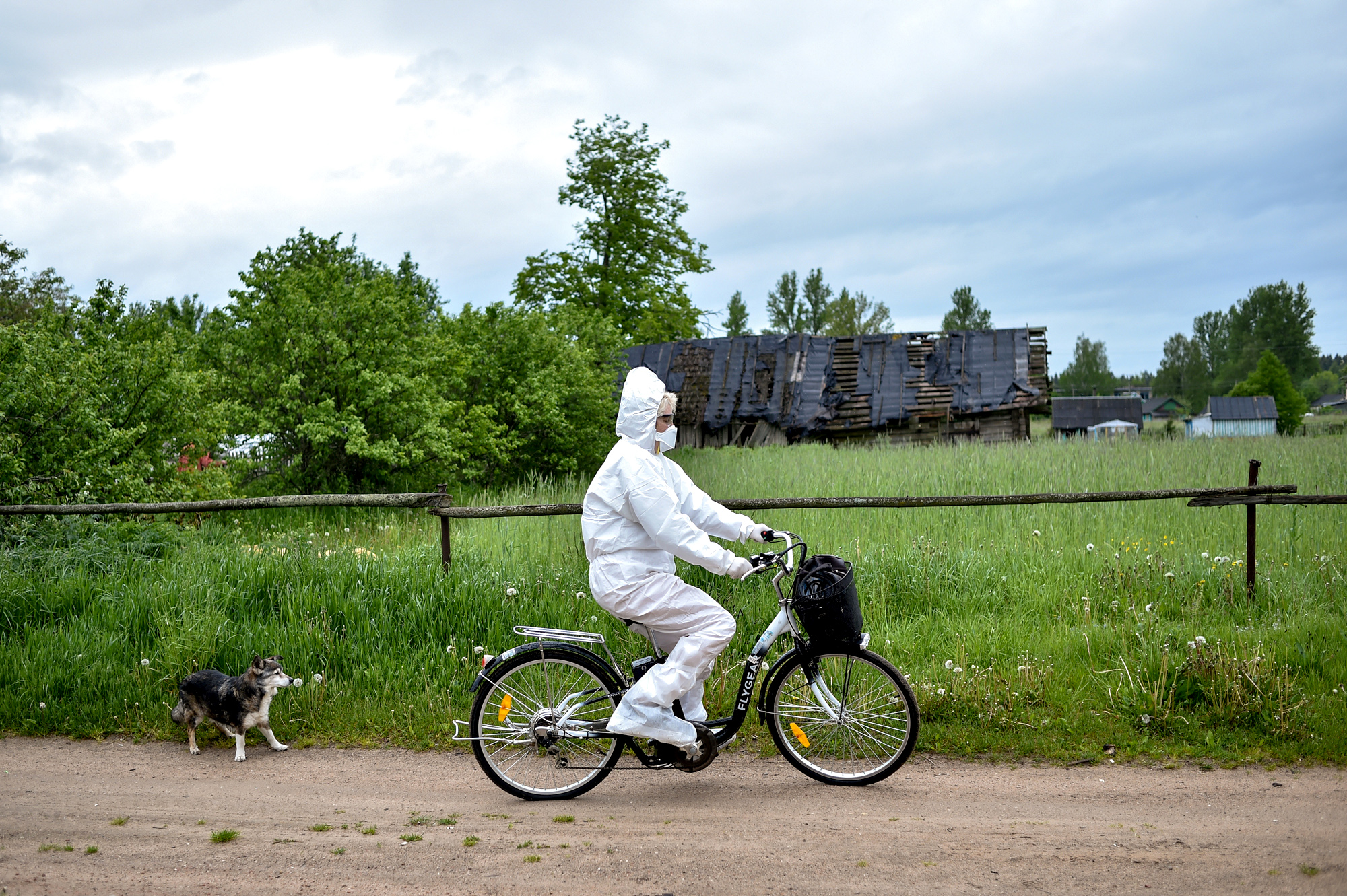 A man riding a bicycle in full protective gear including a facemask. 