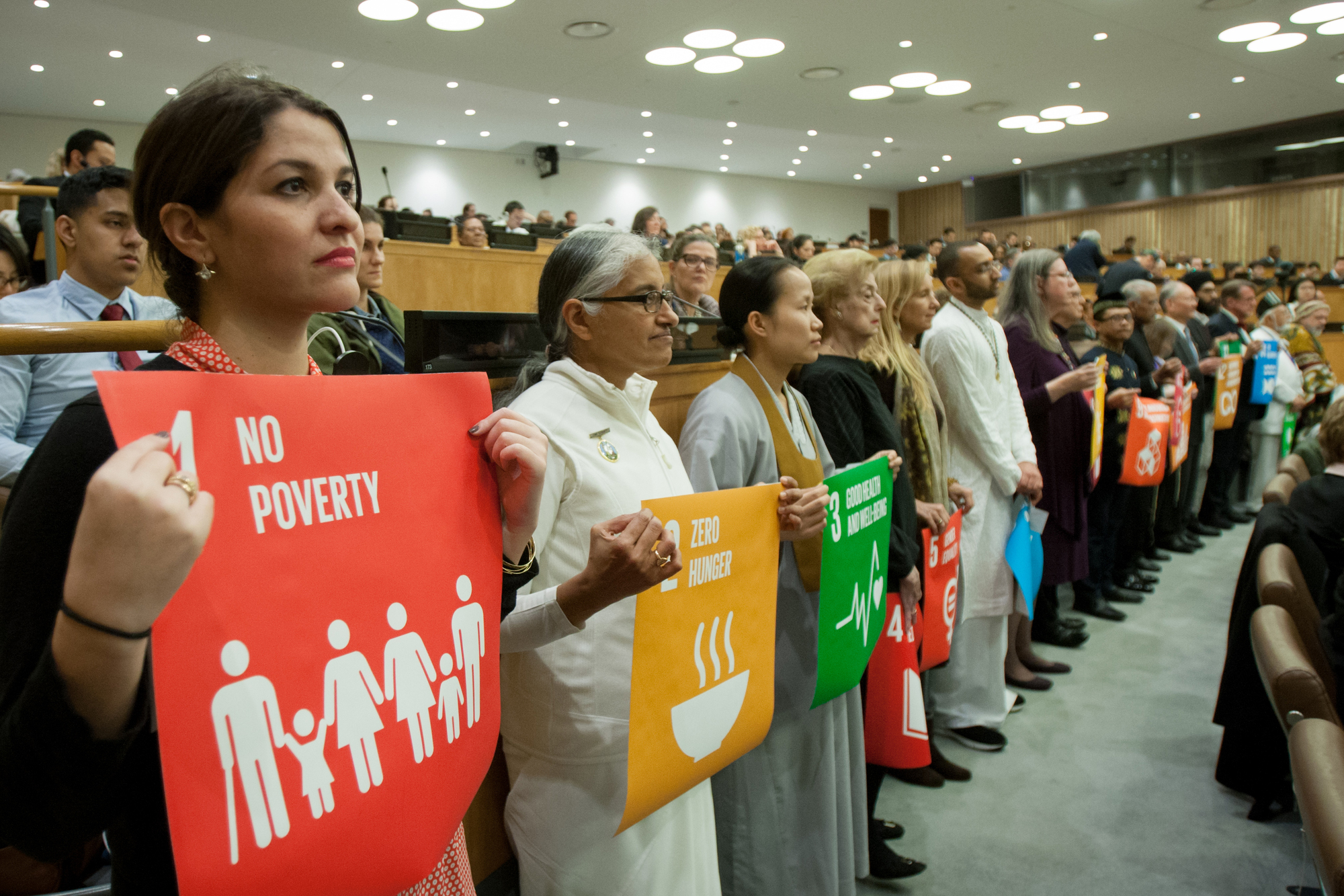 participants at an event at the UN holding up posters of the SDGs