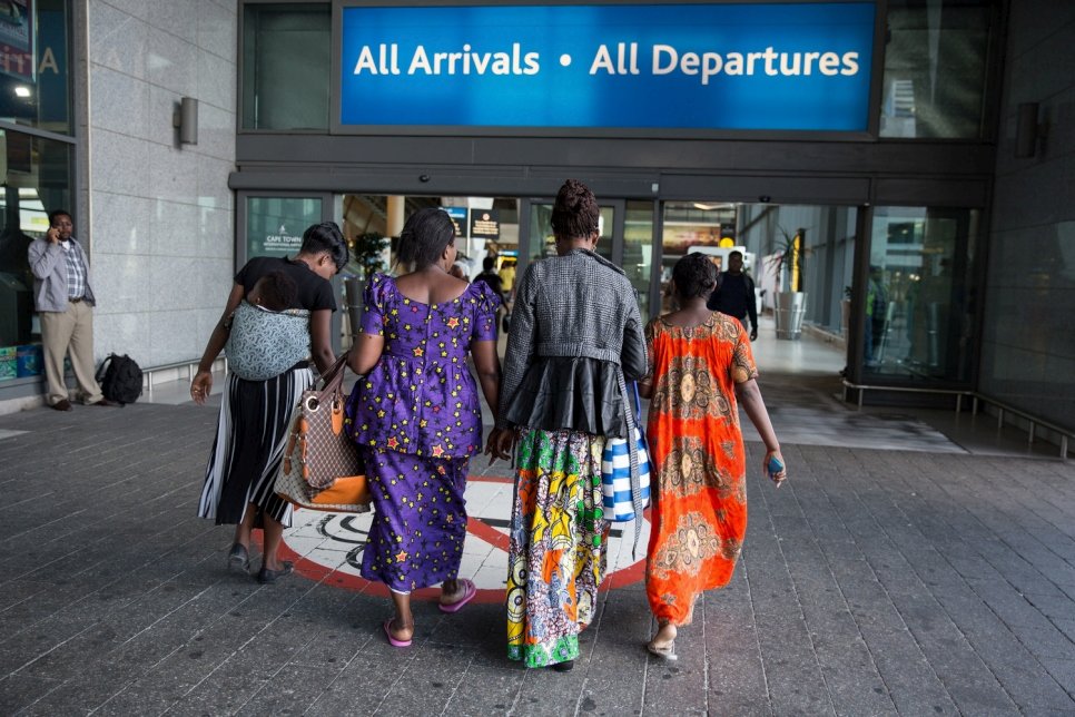 women in African dresses walking towards airport.