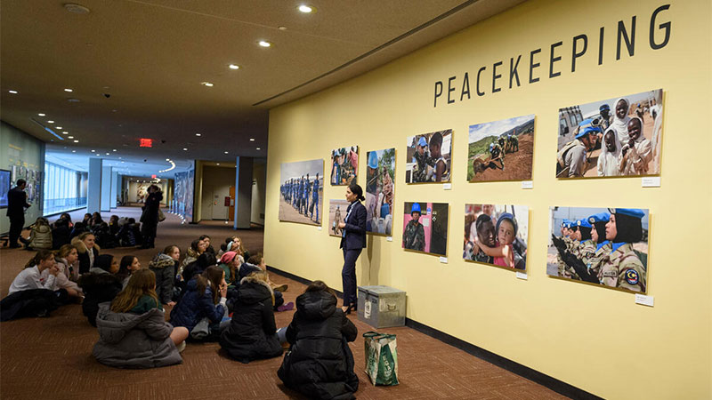Un guía turístico de las Naciones Unidas habla a un grupo de jóvenes visitantes sobre las operaciones de mantenimiento de la paz de las Naciones Unidas.
