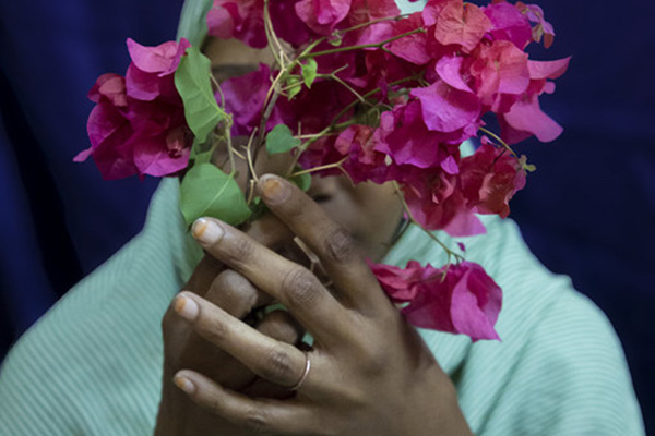 A woman covers her face with flowers.