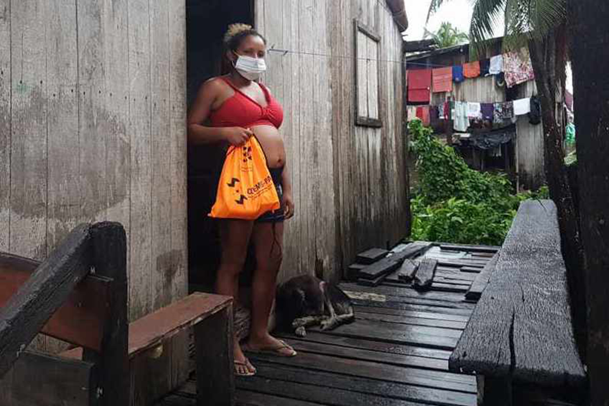 Woman standing at her doorway holds up a full bag.