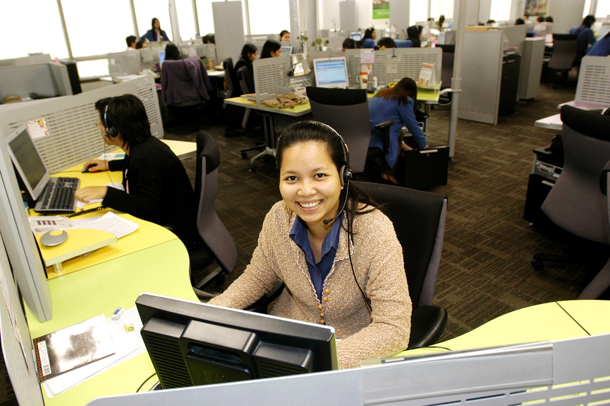 A woman smiles from behind her cubicle.