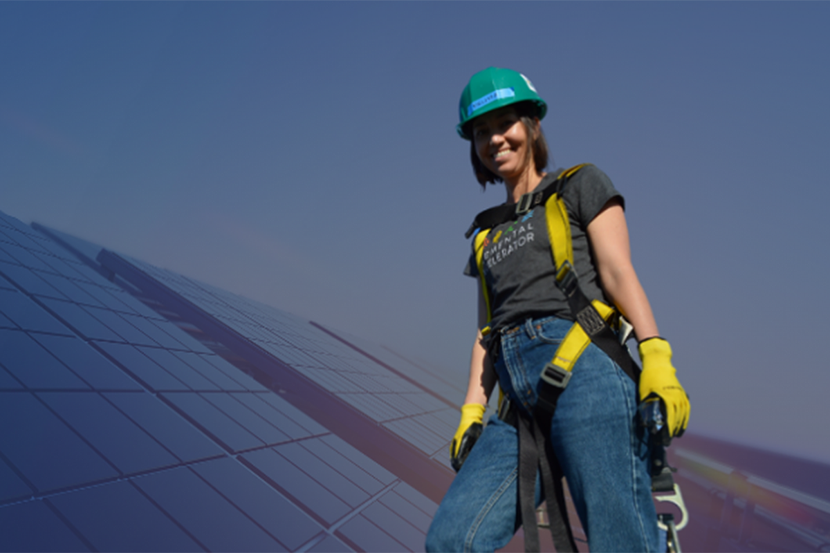 A woman worker in a harness next to solar panels.