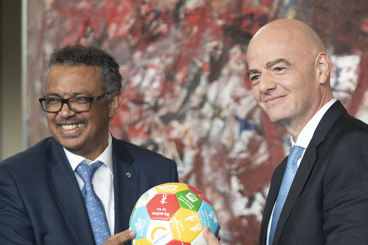 The two organization leaders pose with a football portraying the Sustainable Development Goals.