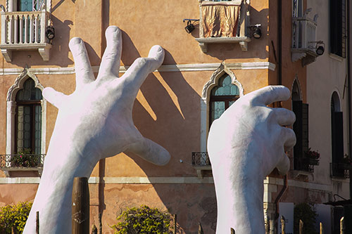 A sculpture of hands placed on the façade of a building