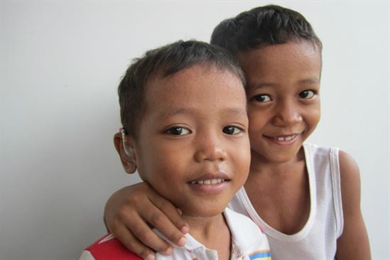 two children, one with hearing aid