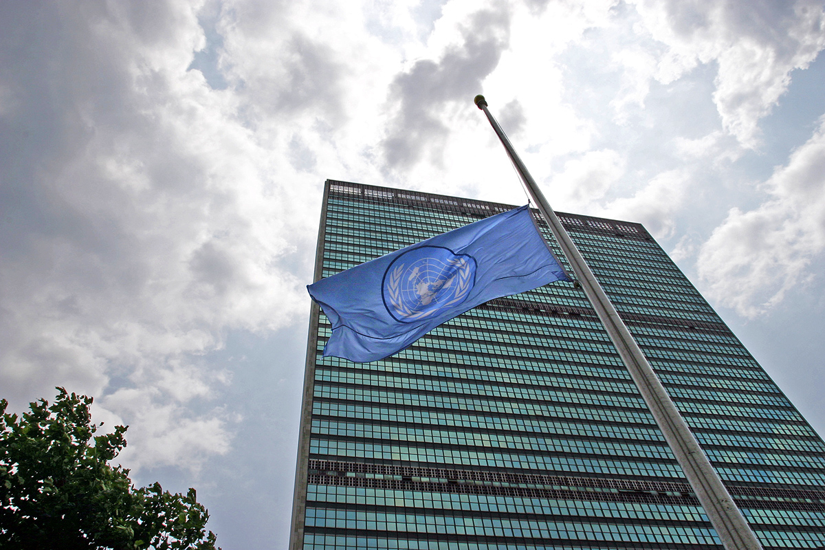 The UN flag at half-mast with the Secretariat building behind. 