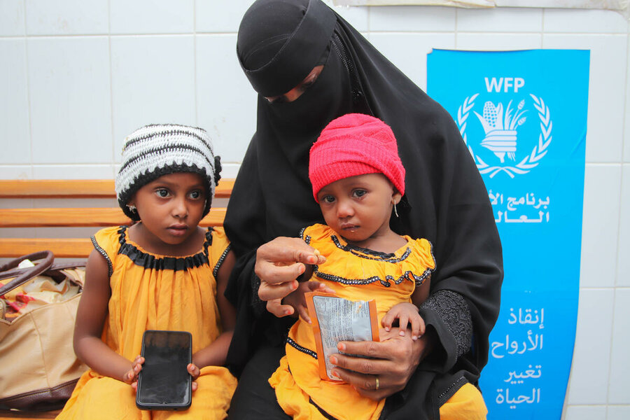 a woman with two little girls receiving supplementary nutrition at a clinic