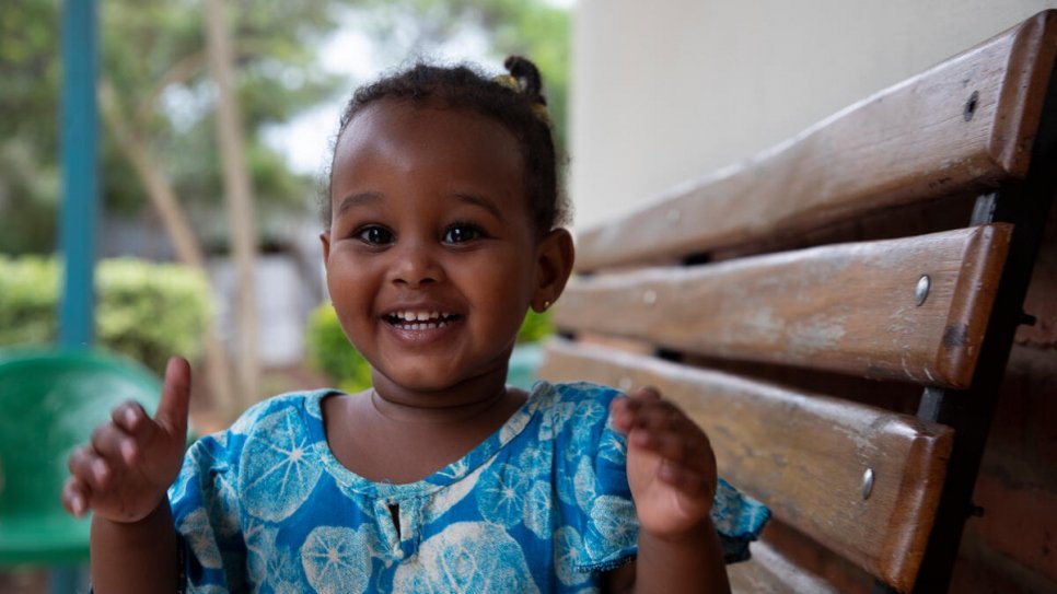 A toddler raises her hands in joy.