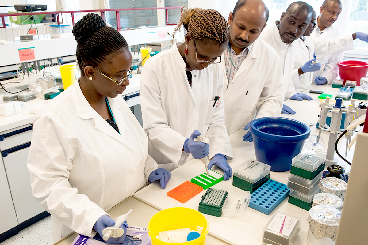 6 men and women in lab coats working at a lab