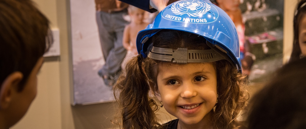 Una niña en el recorrido de niños en la ONU lleva un casco azul de la ONU