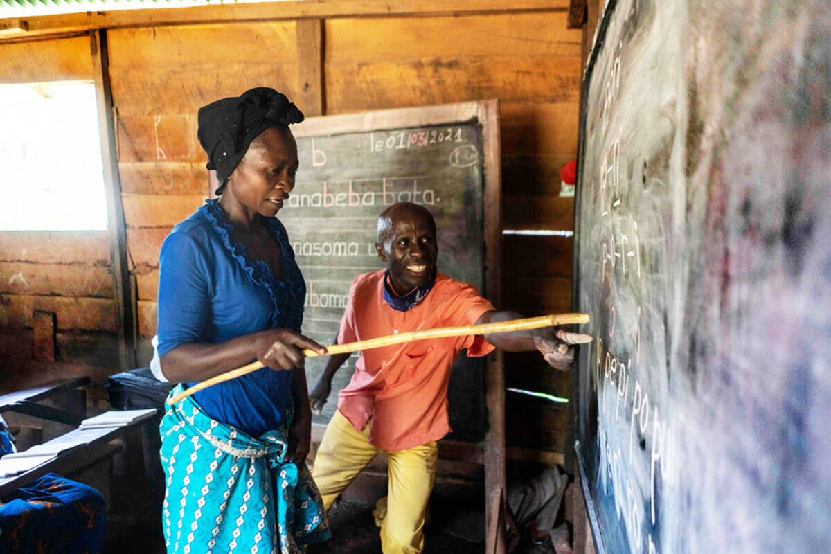 A woman and a man point at a blackboard