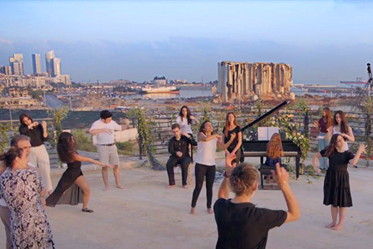 A rooftop with people performing with the Beirut Port as a backdrop.