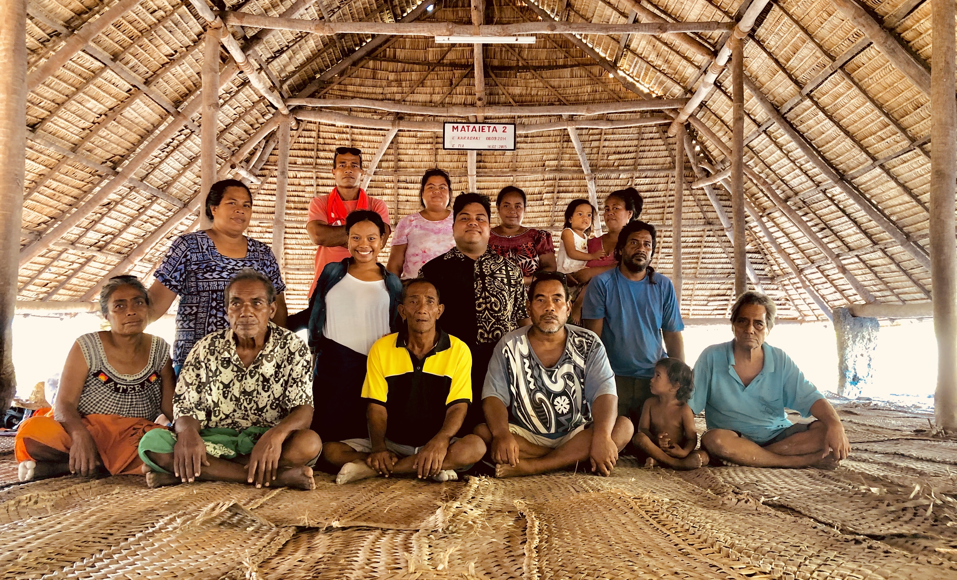 Fotografía de un grupo de personas dentro de una construcción hecha de palma en Kiribati.