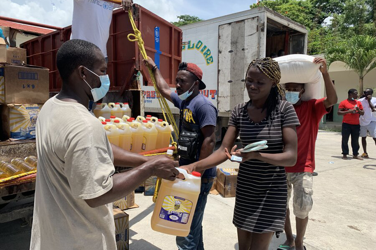 A woman receives cooking oil from a truck.