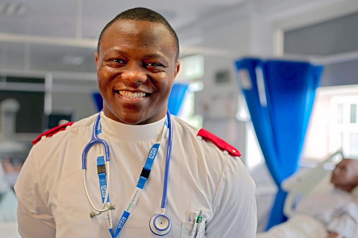 Cyrille in a nurse uniform with a big smile. 