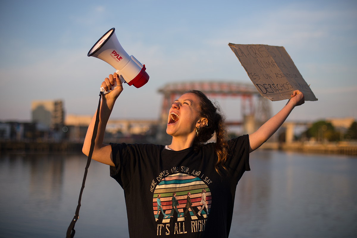 A girl carries a sign and screams into a bullhorn