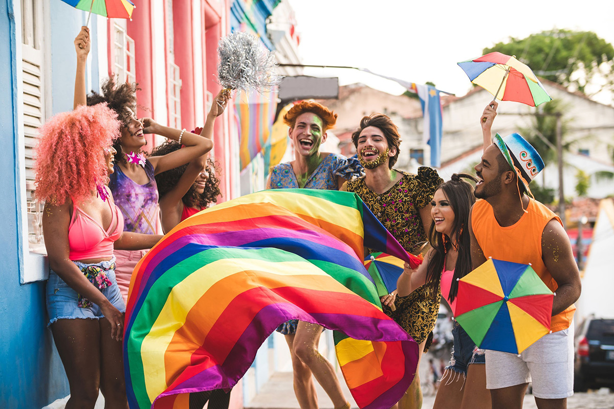 A group of young people around LGBTIQ+ flags and symbols