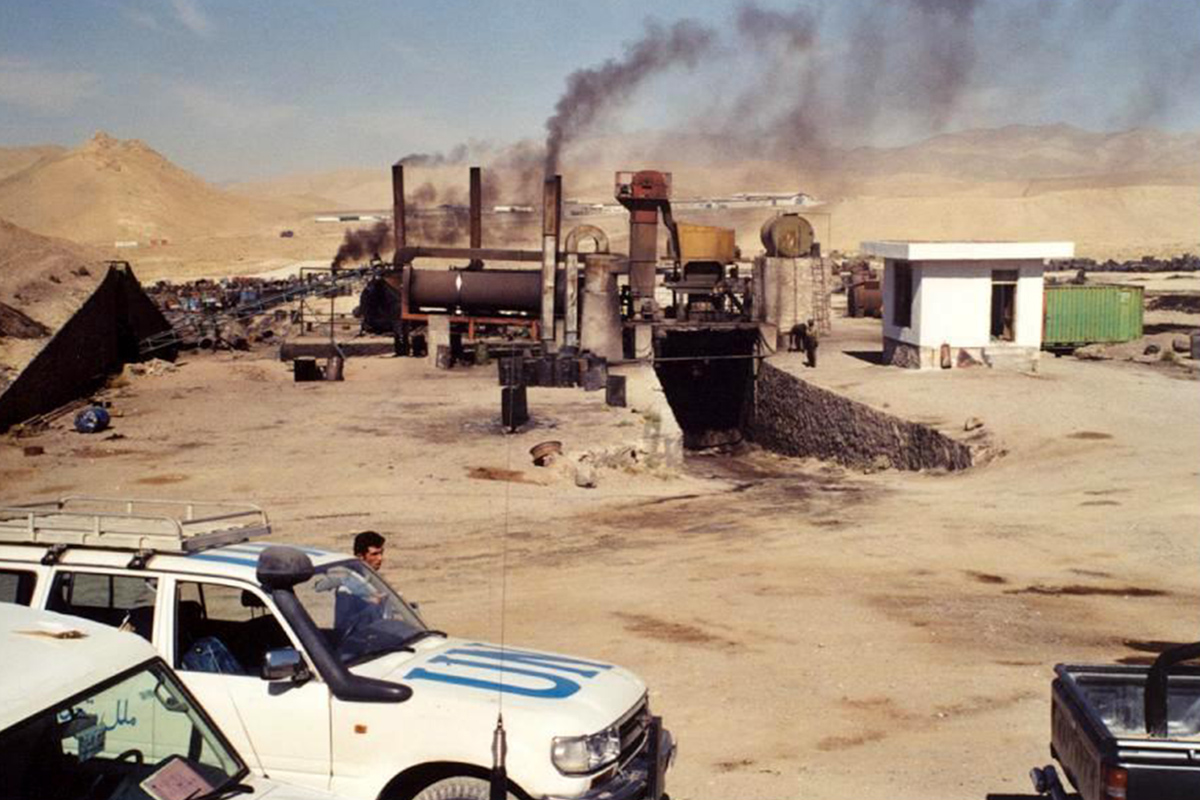 An industrial plant in the desert emitting black smoke